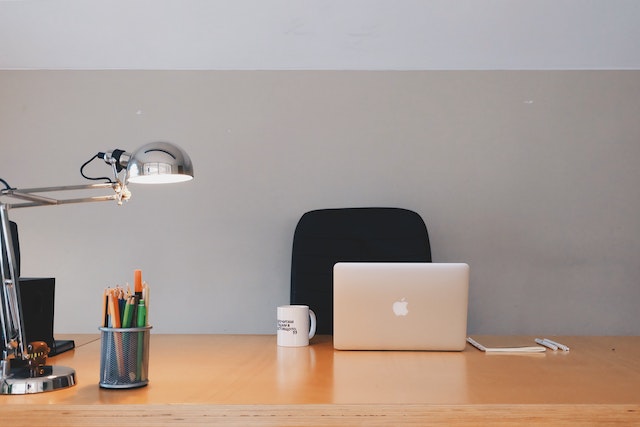 desk setup with a laptop, mug, and lamp